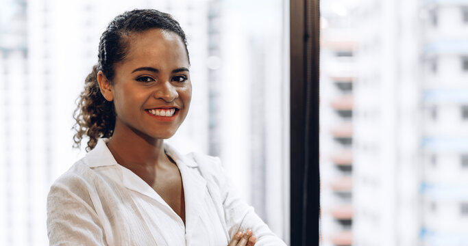 Smiling beautiful professional business african american black woman with arms crossed standing in office