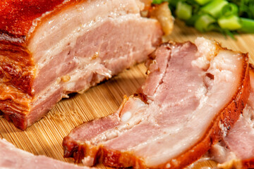 smoked meat cut into slices lies on a wooden table