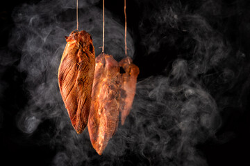 smoked chicken white meat in the process of smoking on a black background