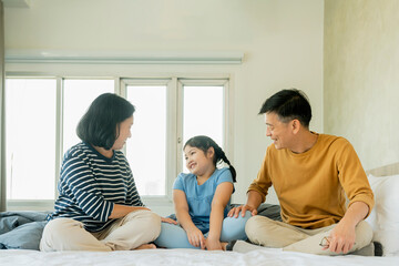 asian Senior grandparents couple laying with grandchildren preety female child on bed in bedroom,happy family play together in the bed
