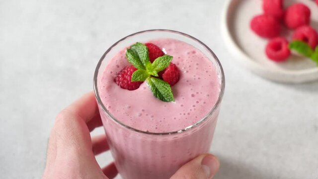 Pink raspberry smoothie in a glass with paper drinking straw. Mixing pink berry smoothie