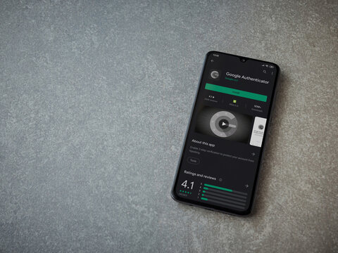 Lod, Israel - July 8, 2020: Google Authenticator app play store page on the display of a black mobile smartphone on ceramic stone background. Top view flat lay with copy space.