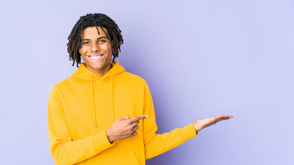 Young african american rasta man excited holding a copy space on palm.