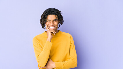 Young black man wearing rasta hairstyle smiling happy and confident, touching chin with hand.