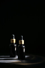 Obraz na płótnie Canvas Pipette black glass dropper bottle with golden elements on the dark background