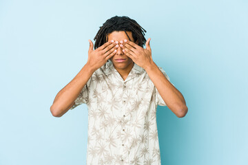Young african american rasta man afraid covering eyes with hands.