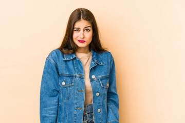 Young caucasian woman isolated en beige background shrugs shoulders and open eyes confused.