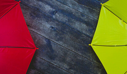 Two umbrellas red and yellow on a wooden background top view. Space for text, copy space.