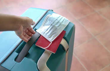 Hand carrying luggage bag with face mask and passport.