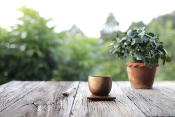 Traditional brown wooden cup with notebooks and white plant pot on wooden table