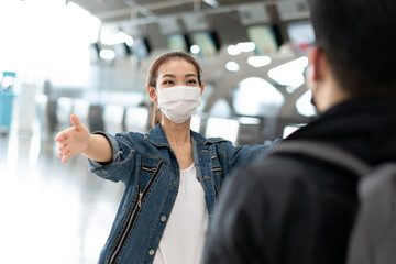 Asian woman wearing protective mask running to embrace friend or boyfriend at arrival gate in airport terminal. welcome back home from study or working abroad during coronavirus pandemic