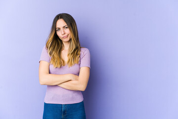Young caucasian woman isolated on purple background frowning face in displeasure, keeps arms folded.