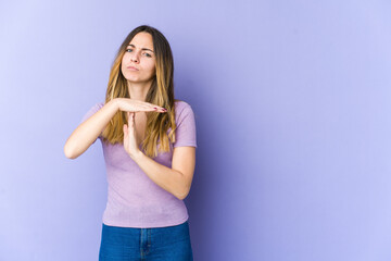 Young caucasian woman isolated on purple background showing a timeout gesture.