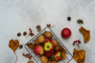 autumn decor background with copy space text or design, dry leaves, apples, walnuts in shell, acorns, rowan in basket, autumn food concept and happy thanksgiving day