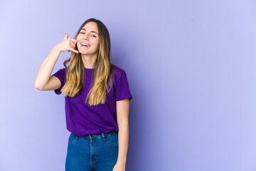 Young caucasian woman isolated on purple background showing a mobile phone call gesture with fingers.