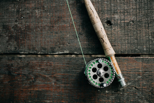 Wallpaper or texture of fly fishing rod lying on old wooden table. High angle view.
