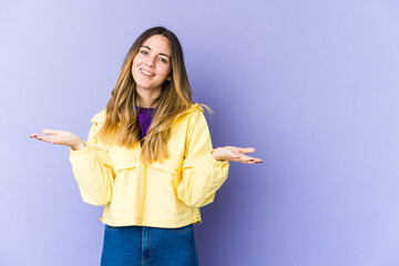 Young caucasian woman isolated on purple background makes scale with arms, feels happy and confident.