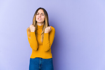 Young caucasian woman isolated on purple background upset screaming with tense hands.