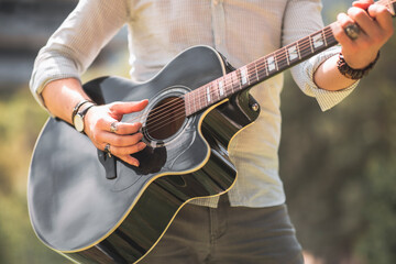 Anonymous man is playing a guitar at outside in autumn season with trendy orange colors, headless photo with copy space.