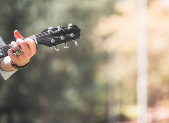 Anonymous man is playing a guitar at outside in autumn season with trendy orange colors, headless...