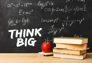 Books, apple think big text over school blackboard