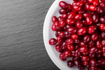Dogwood berries in a white plate on a black board.