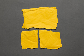 Torn real paper yellow color scraps on gray background