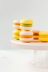 Colorful french macarons on a pink plate on white background