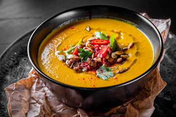 Pumpkin soup in black plate on black wooden table background