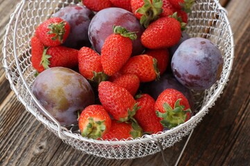 Ripe plums and strawberries on a wooden table