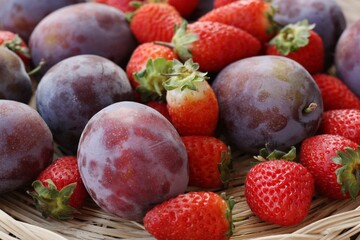 Ripe plums and strawberries on a wooden table