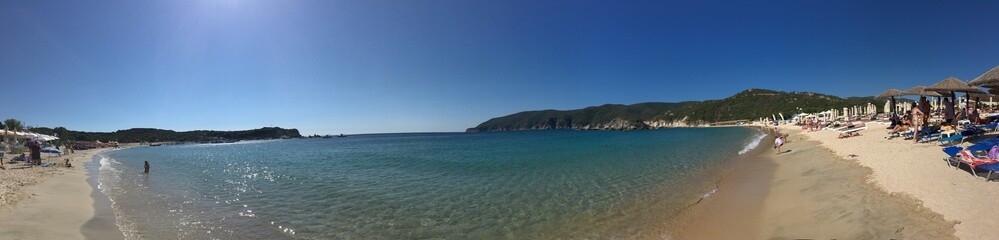 Sunny beach panorama in Greece on sunny day with mountain on background clear blue sky