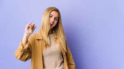 Young blonde woman isolated on purple background laughing about something, covering mouth with hands.