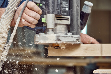 Carpenter with hand electric router machine at work. Milling process of acrylic kitchen countertop