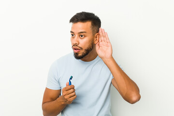 Young south-asian man holding a razor blade trying to listening a gossip.
