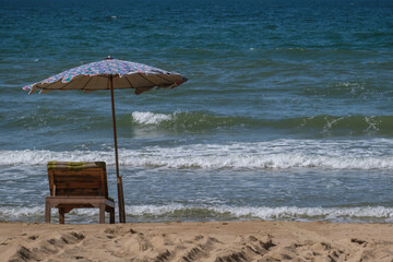 Striped sun umbrella and white beach loungers. Beach umbrella and couches on blue sky and sea background on the beach of Italy. Popular Tourist Resort at Adriatic Sea, Rayong Thailand