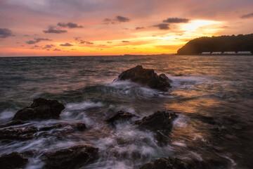 Amazing beach sunset with endless horizon and lonely figures in the distance, and incredible foamy waves.Rayong Beach, Thailand