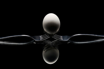 egg placed on forks on a dark background