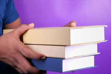 hand holding stack of books on color background 