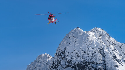 Fototapeta na wymiar Rescue helicopter saved mountain climbers. People on the top of Swinica steep and rocky mountain peak at winter, Tatra Mountains, Poland