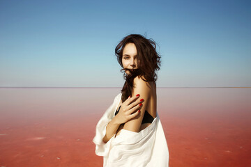 Fototapeta na wymiar beautiful girl on pink salt lake. vacation young brunette woman