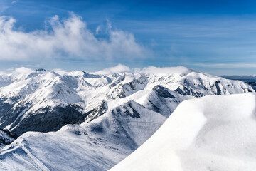 View from Kasprowy Wierch at pine forest with winter coating in the valley. Snow capped mountain peaks of Tatra Mountains, Bukowina Tatrzanska, Poland