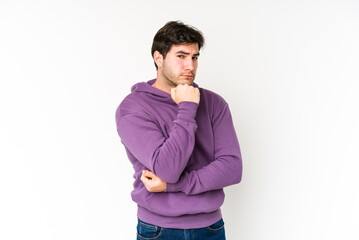 Young man isolated on white background suspicious, uncertain, examining you.