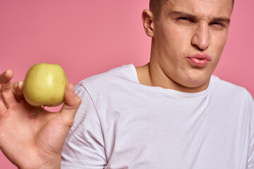 Man with fruits in hands on a pink background healthy food vitamins pink background white t-shirt model