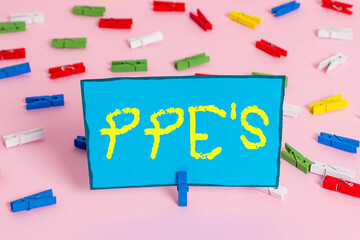 Text sign showing Ppe s is. Business photo showcasing Specialized equipment for protection against health and safety hazard Colored clothespin papers empty reminder pink floor background office pin