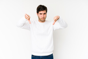 Young man isolated on white background showing a dislike gesture, thumbs down. Disagreement concept.