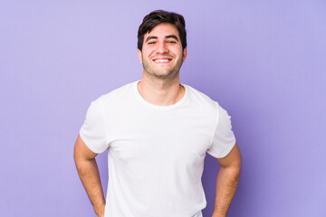 Young man isolated on purple background happy, smiling and cheerful.