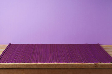 Empty wooden table with bamboo mat over purple background. Kitchen or restaurant counter mockup for design