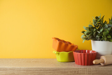 Autumn kitchen interior background with plant and colorful bowls on wooden shelf