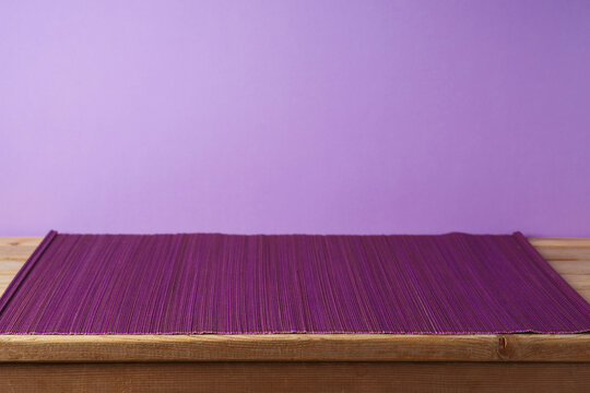 Empty Wooden Table With Bamboo Mat Over Purple Background. Kitchen Or Restaurant Counter Mockup For Design